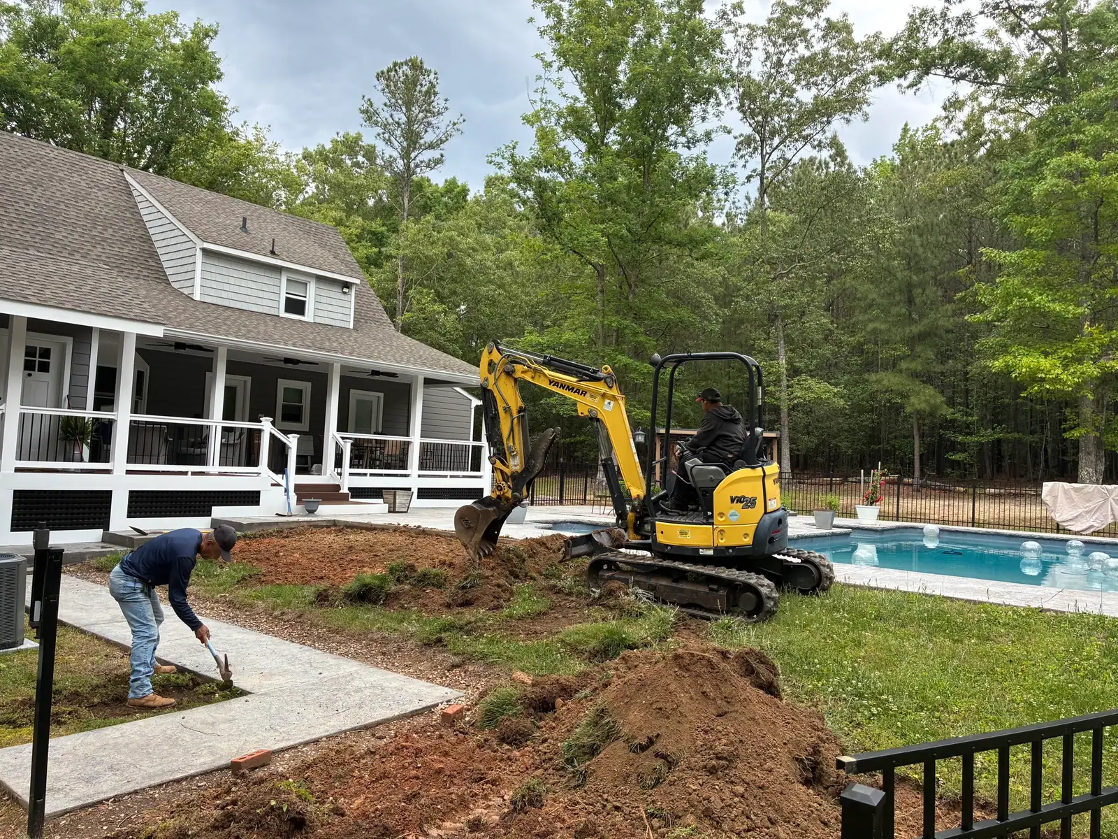 Excavator and crew clearing the poolside lawn