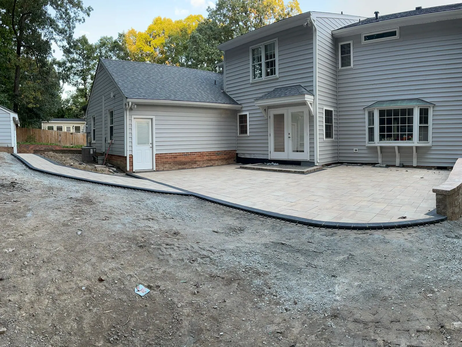 Completed paver patio with a curved edge beside the home