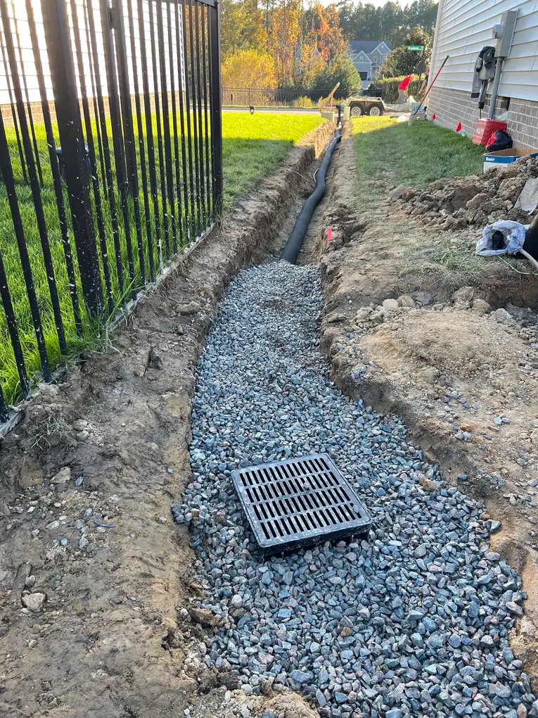 Drainage grate and stone-filled trench along the fence