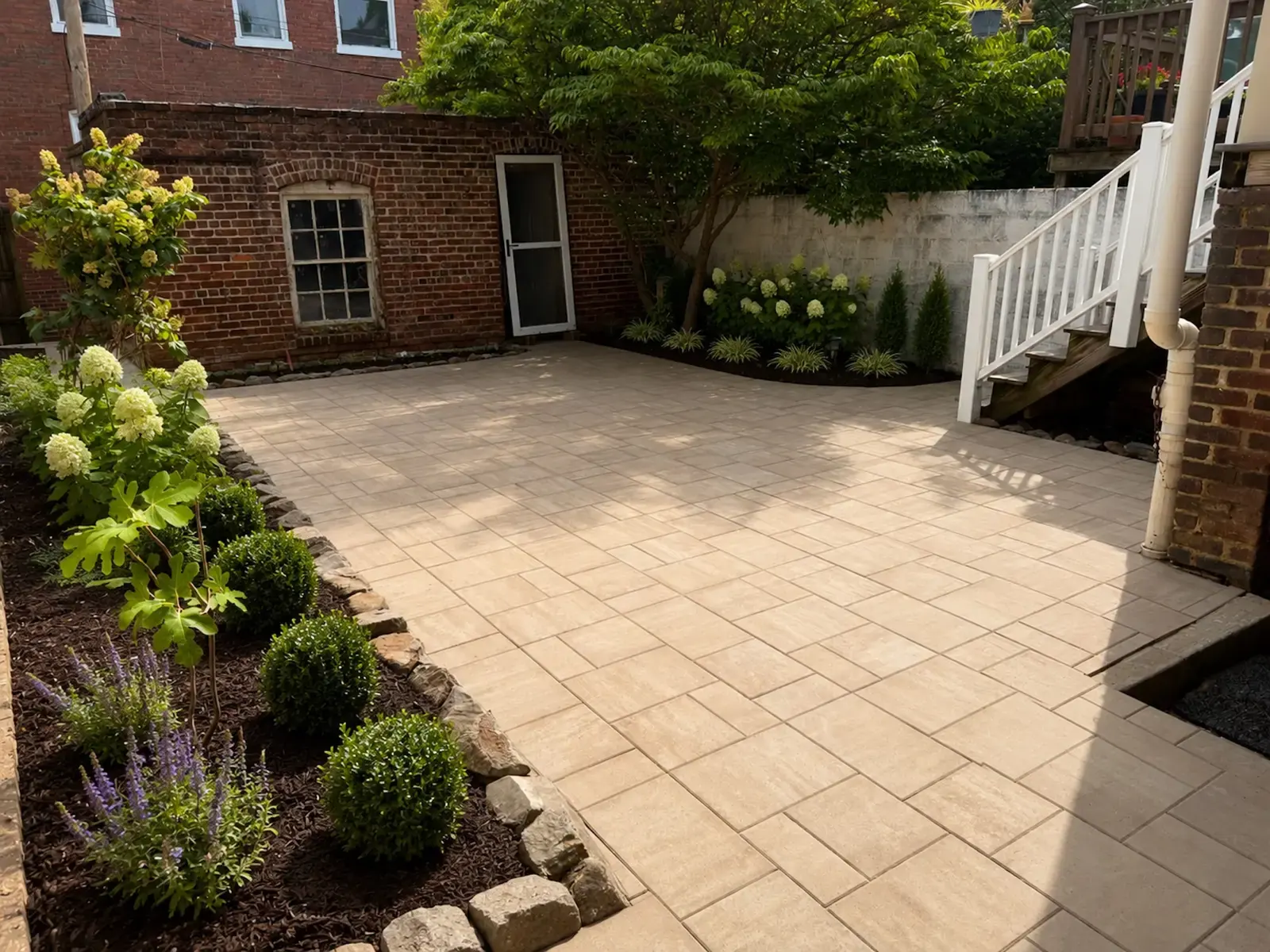 Finished patio and flowering beds beside the brick home
