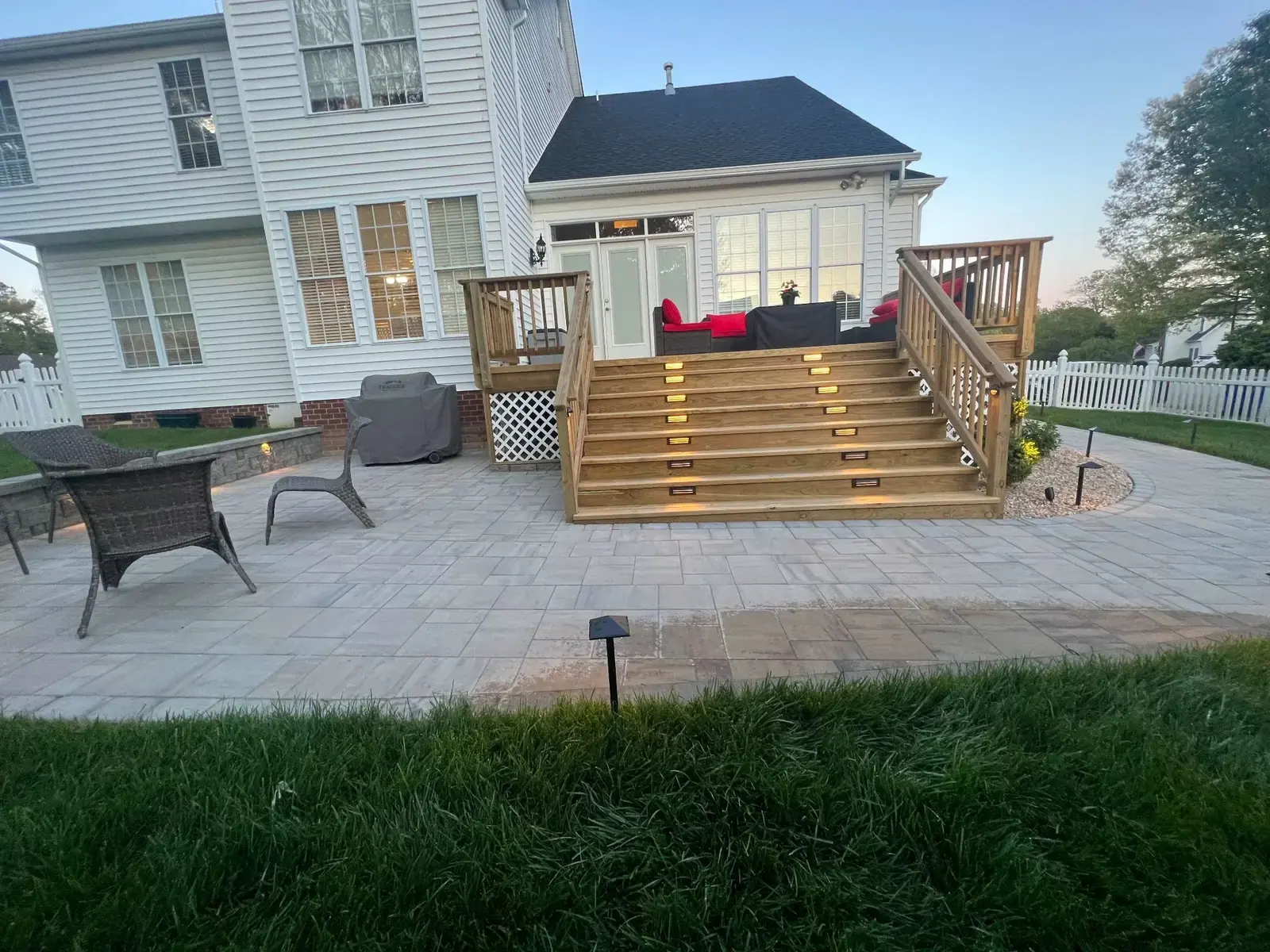 Patio beside illuminated deck stairs