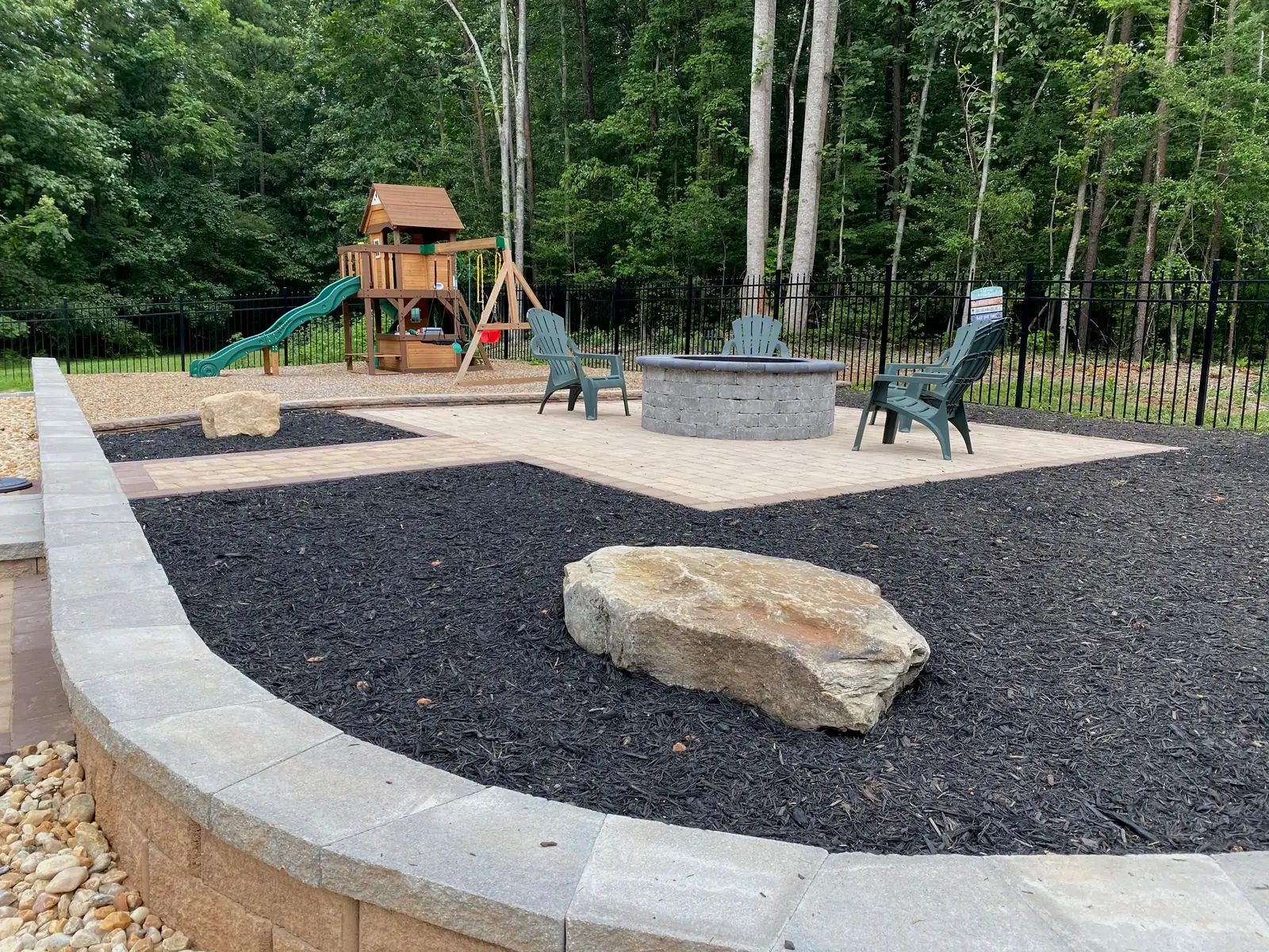 Curved poolside planting bed with boulders and paver edging