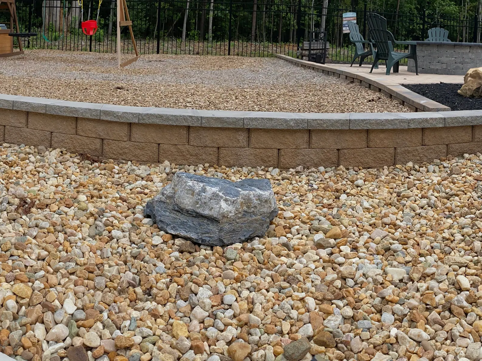 Curved retaining wall bordering river rock beside the pool