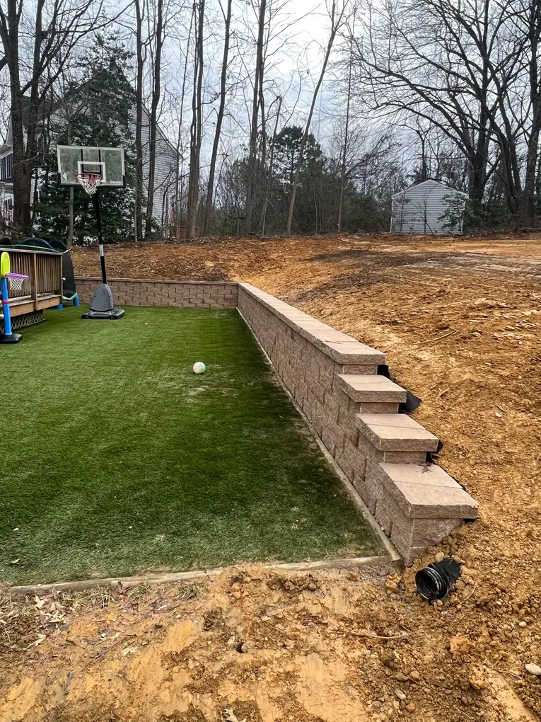 Retaining Wall: Capped retaining wall beside the backyard artificial lawn