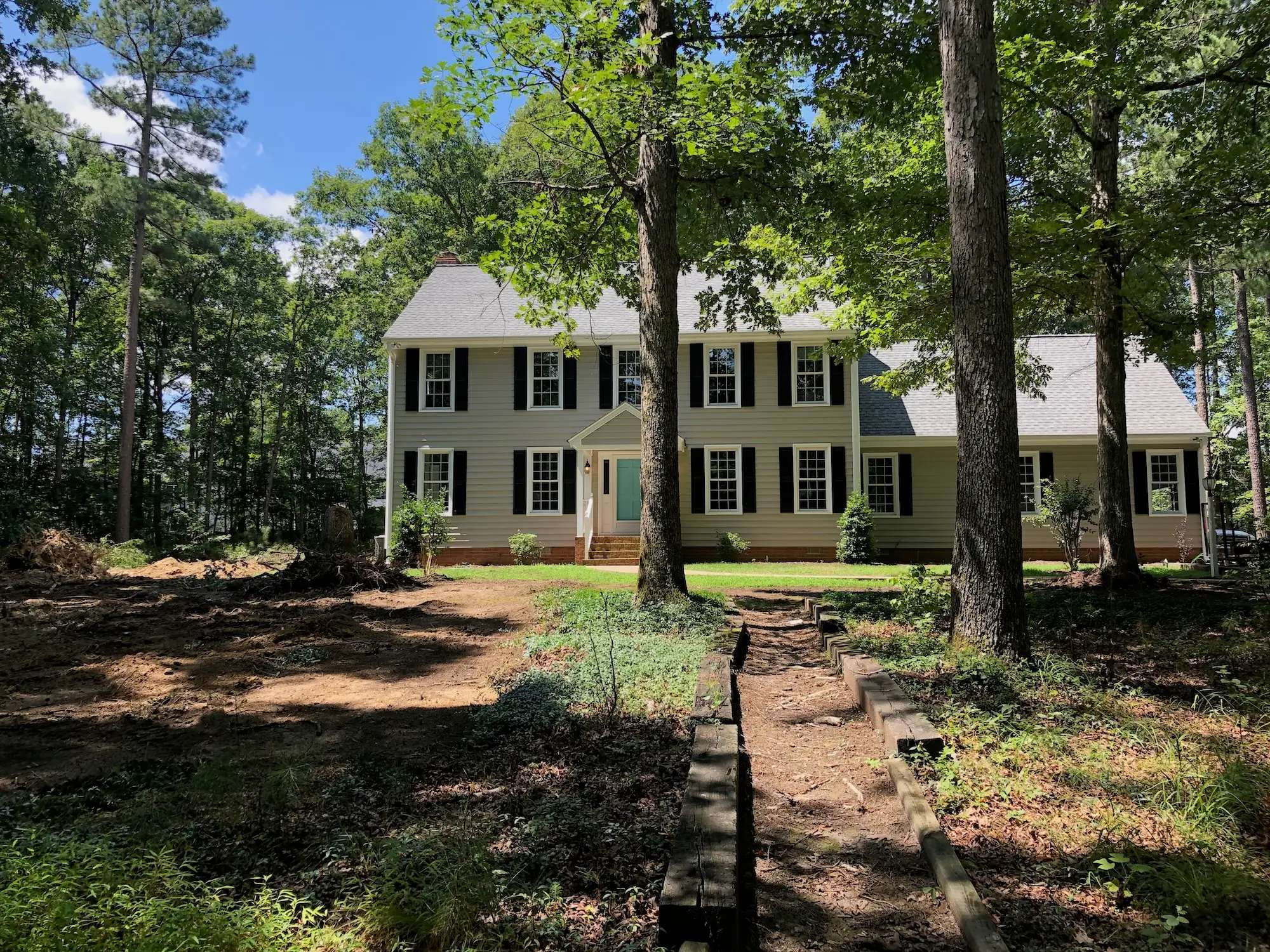 Hames property before work, with uneven ground and trees around the house